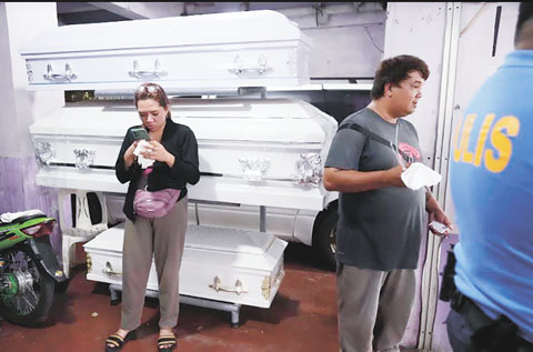 7月11日，甲美地省，菲律濱親屬在一間停屍房等待。官員們說，兩名澳洲公民和他們的菲律濱同伴在酒店被殺，警方正在努力查明和追捕嫌疑人。（美聯社）