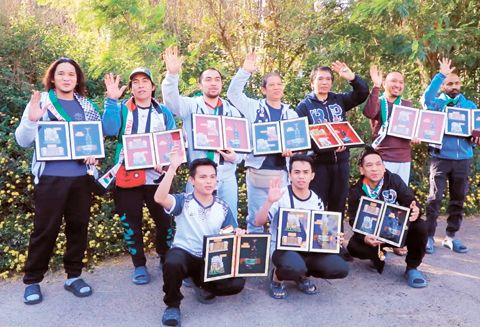 這張12月3日的視頻截圖顯示,在也門首都薩那國際機場,被釋放的船員在登機前手持紀念品合影。(新華社)