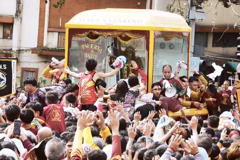 信徒們於1月9日清晨在馬尼拉的亞耶拉橋附近簇擁著黑耶穌聖像。一些人將他們的手帕及其他衣物扔給最靠近神像車輦的信徒,供其擦拭聖像。