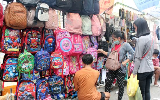 8月10日，家長們在巴蘭玉計市的墨拉蘭菜市查看出售的書包。