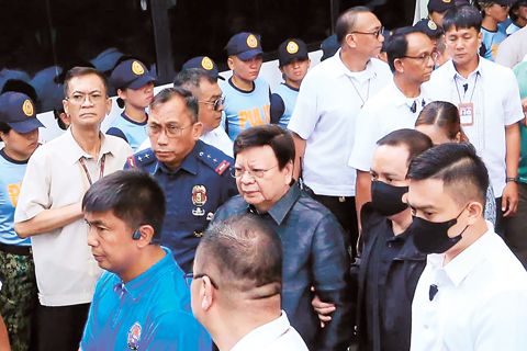 參議員羅丹特·馬科禮沓(中)於週一在計順市廉政法庭被捕時,由警方押送。他因涉嫌掠奪罪而被捕。(美聯社)