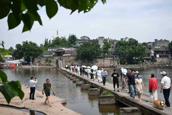 6月14日，游客在万灵古镇大荣桥上游玩。中新社记者