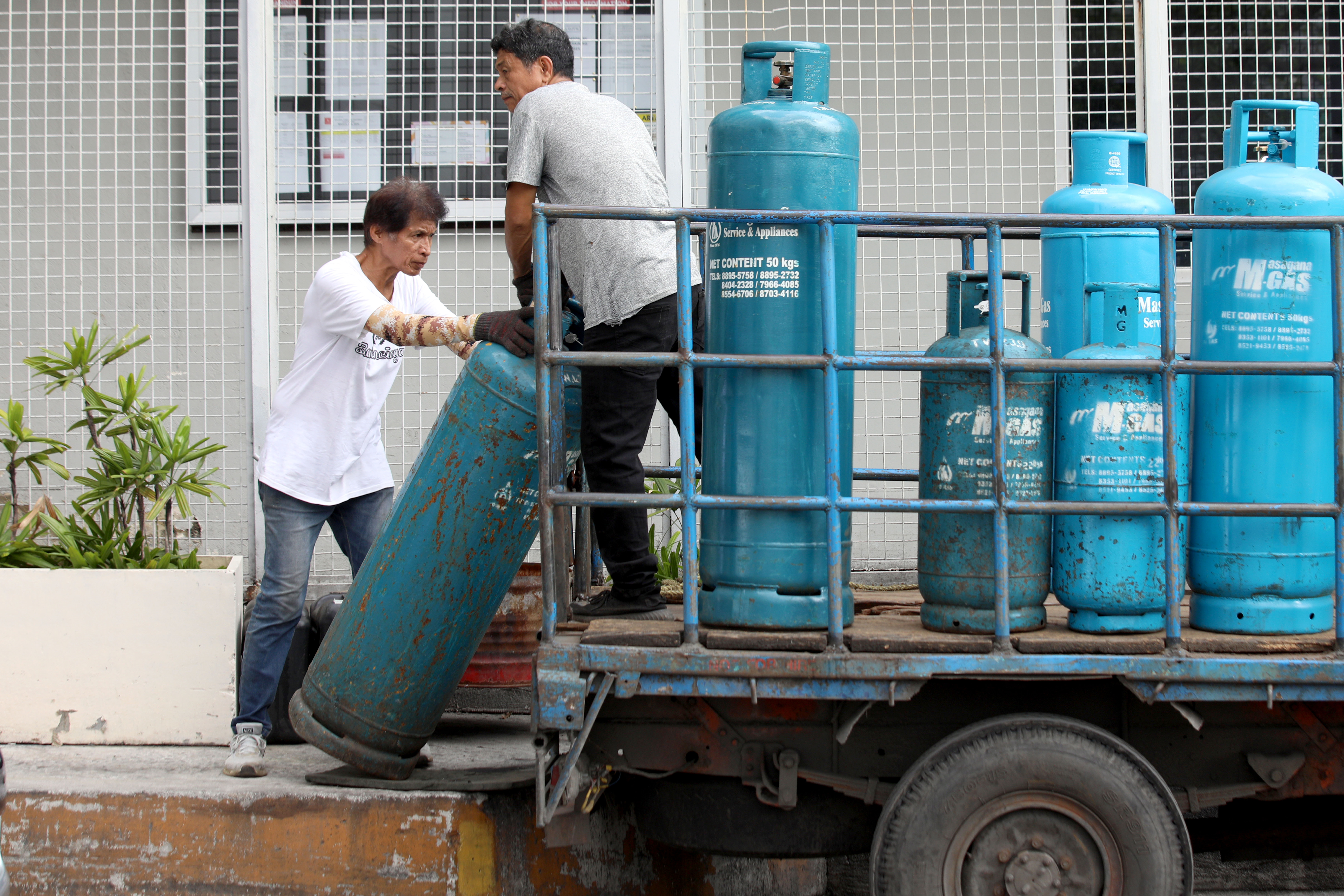 工人8日在馬尼拉的一家酒店卸下液化石油氣罐。液化石油氣價格每公斤漲價20披索。