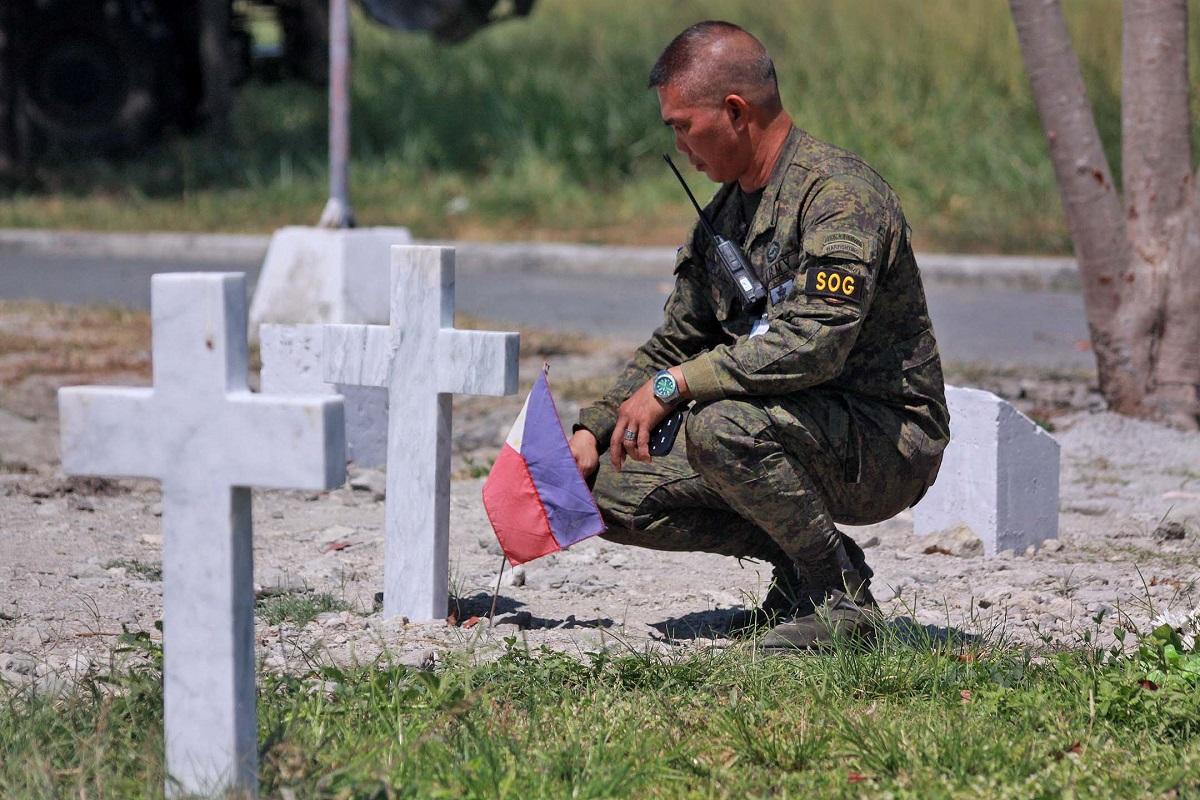 在「英勇日」前夕,一名菲陸軍士兵在英雄墓園為在二戰中喪生的親屬墓前放置國旗。